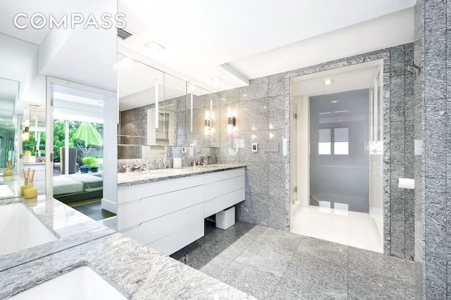 bathroom with tile walls, connected bathroom, healthy amount of natural light, and vanity