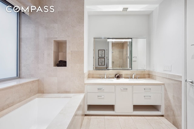 full bathroom with tile walls, tile patterned flooring, a garden tub, double vanity, and tiled shower
