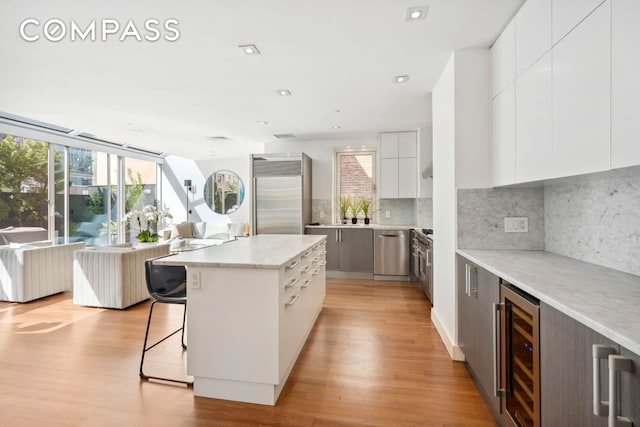 kitchen featuring beverage cooler, stainless steel appliances, modern cabinets, plenty of natural light, and recessed lighting