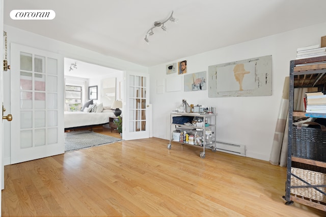 bedroom with baseboard heating, wood finished floors, track lighting, french doors, and visible vents