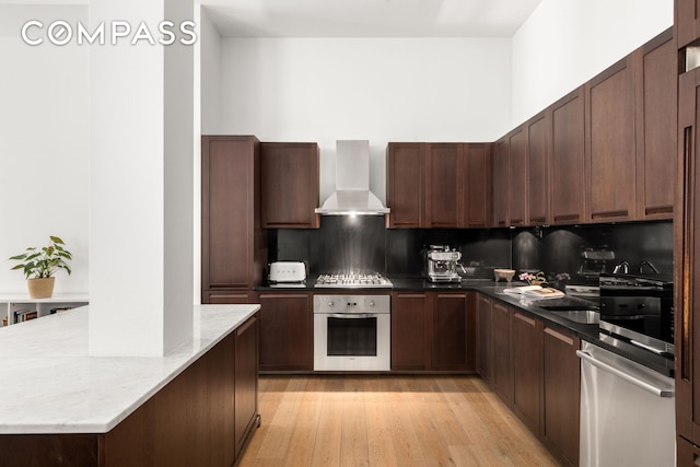 655 6th Ave Unit 5H, New York City, NY 10010 - kitchen featuring stainless steel appliances, range hood, backsplash, light wood finished floors, and light stone counters