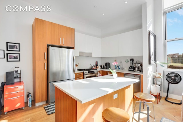 220 W 148th St Unit 3K, New York City, NY 10039 - kitchen featuring appliances with stainless steel finishes, a kitchen bar, light countertops, a center island, and white cabinetry