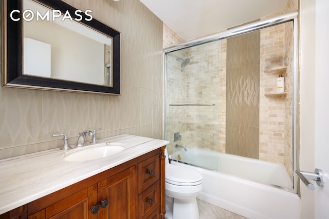 bathroom with vanity, toilet, enclosed tub / shower combo, and tile walls