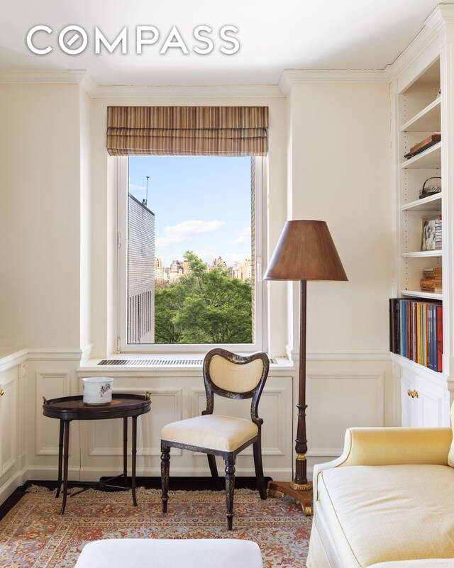 1049 5th Ave Unit 17A, New York City, NY 10028 - sitting room featuring crown molding, a wainscoted wall, and a decorative wall