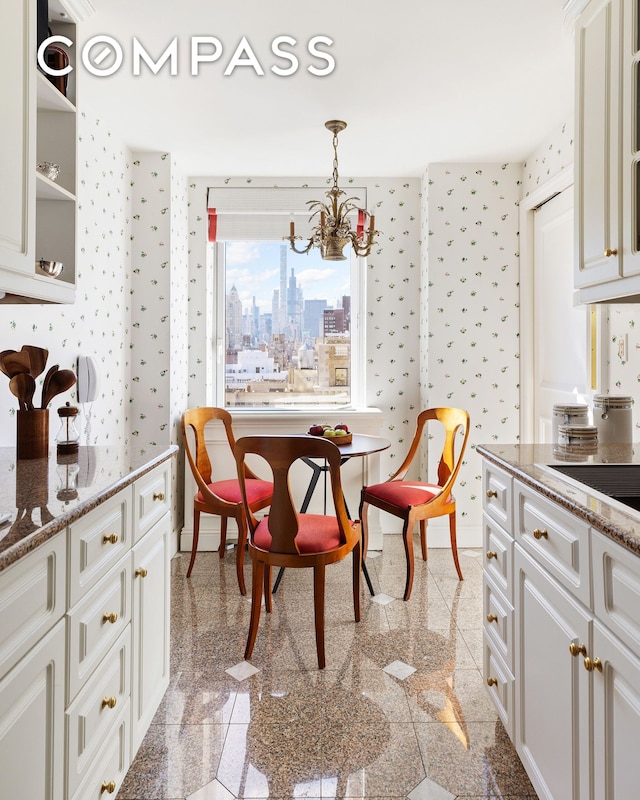 dining room featuring baseboards, a chandelier, granite finish floor, and wallpapered walls