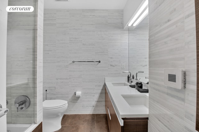 bathroom with toilet, tile patterned floors, a sink, and tile walls