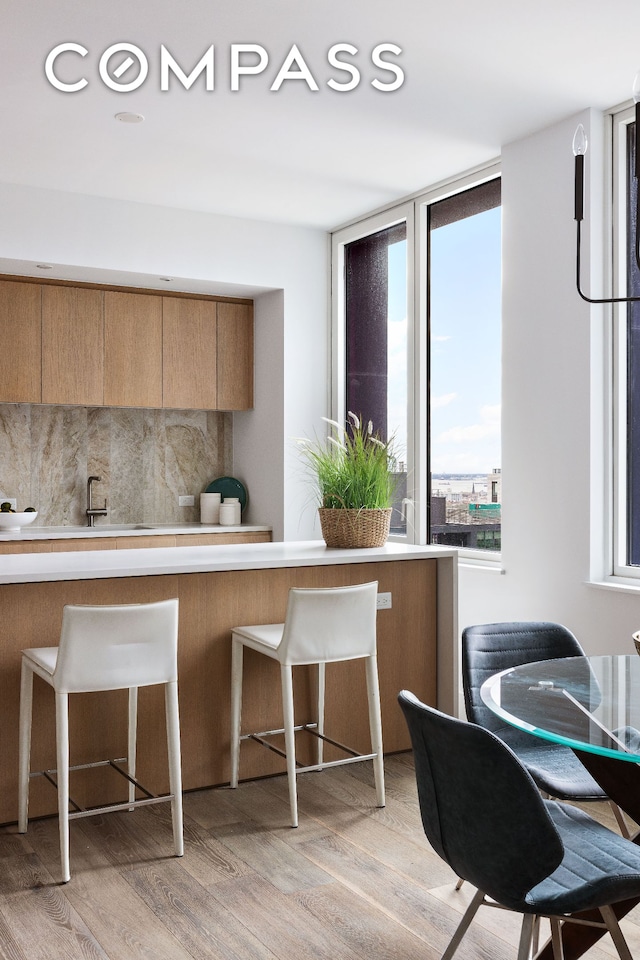 10 Nevins St Phb, Phb, New York City, NY 11217 - kitchen with light wood-type flooring, decorative backsplash, a breakfast bar, and healthy amount of natural light