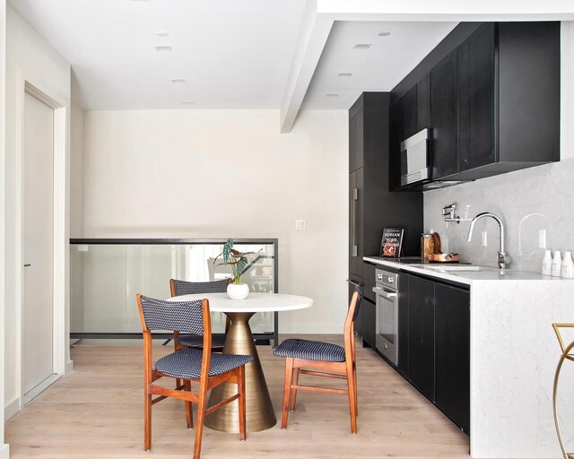 156 Devoe St Unit 1F, New York City, NY 11211 - kitchen with dark cabinetry, stainless steel oven, light countertops, and decorative backsplash