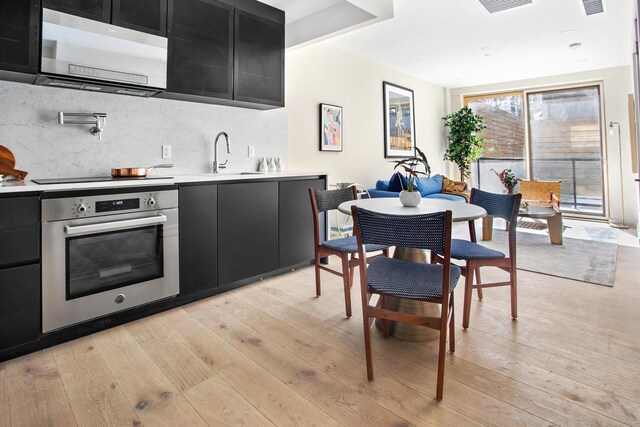156 Devoe St Unit 1F, New York City, NY 11211 - kitchen featuring oven, dark cabinetry, a sink, and light countertops