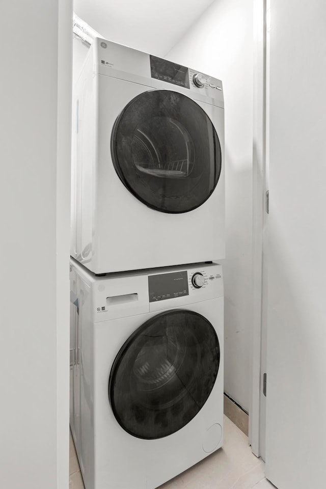 laundry area with stacked washing machine and dryer and light tile patterned floors