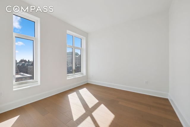 empty room featuring hardwood / wood-style flooring and baseboards