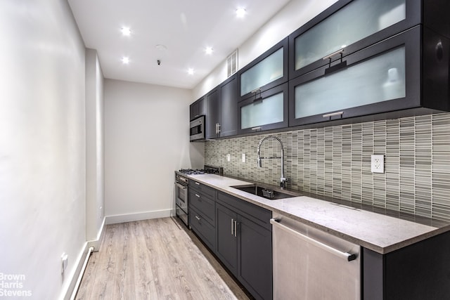 41 E 28th St Unit 2B, New York City, NY 10016 - kitchen featuring a sink, appliances with stainless steel finishes, backsplash, light wood-style flooring, and baseboards
