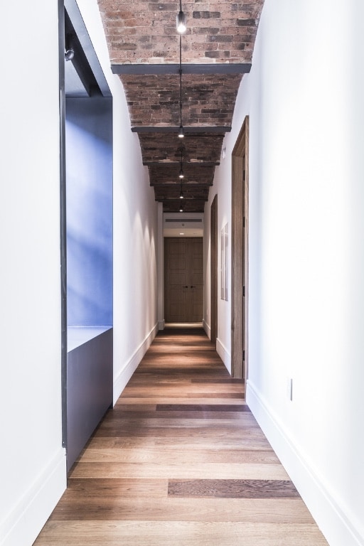 36 Bleecker St Unit 4A, New York City, NY 10012 - hall featuring brick ceiling, wood finished floors, and baseboards