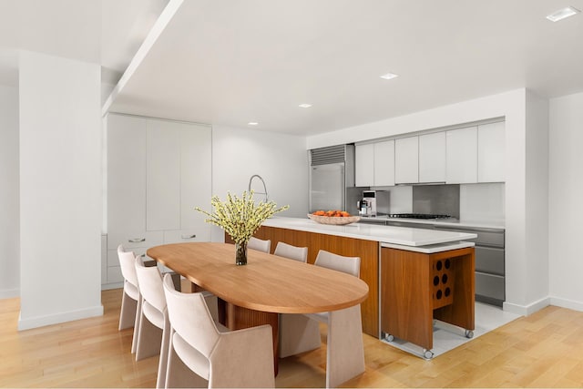 kitchen featuring light wood finished floors, modern cabinets, baseboards, light countertops, and recessed lighting