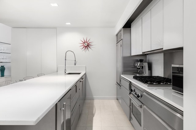 kitchen featuring stainless steel appliances, beverage cooler, baseboards, a peninsula, and a sink