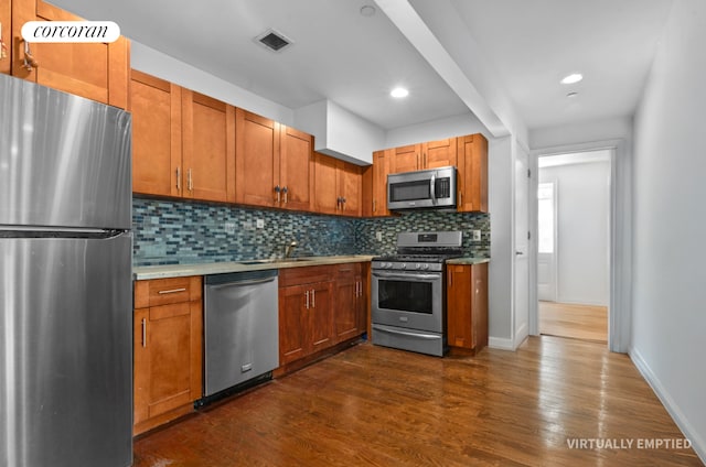 1138 Ocean Ave Unit 7G, New York City, NY 11230 - kitchen featuring brown cabinets, tasteful backsplash, stainless steel appliances, dark wood-type flooring, and visible vents