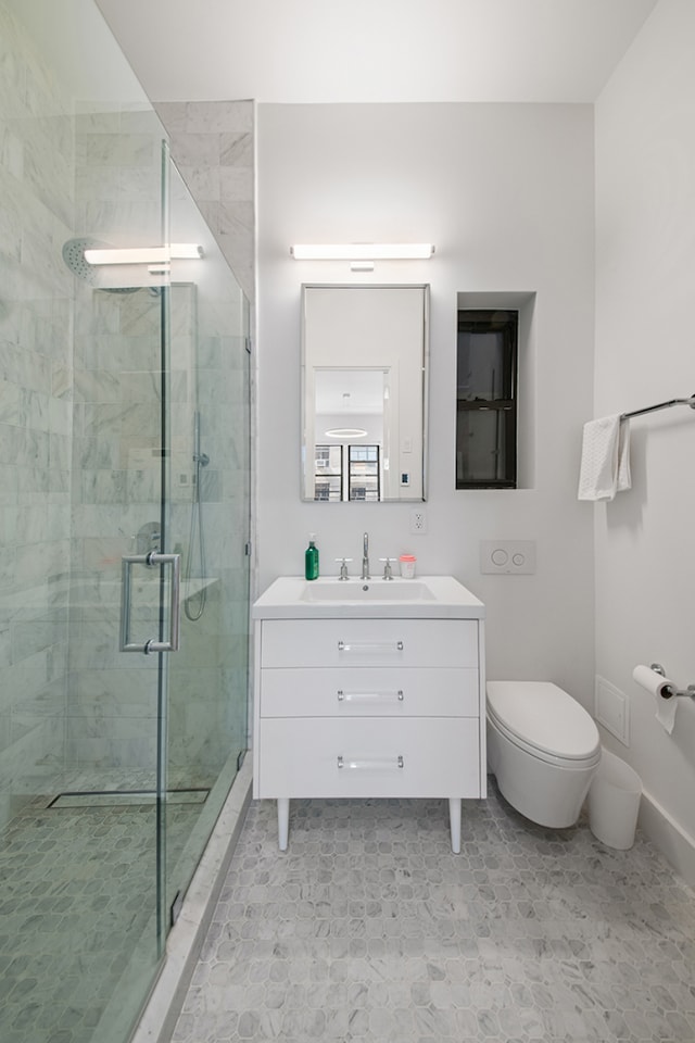 bathroom with a shower stall, vanity, and toilet