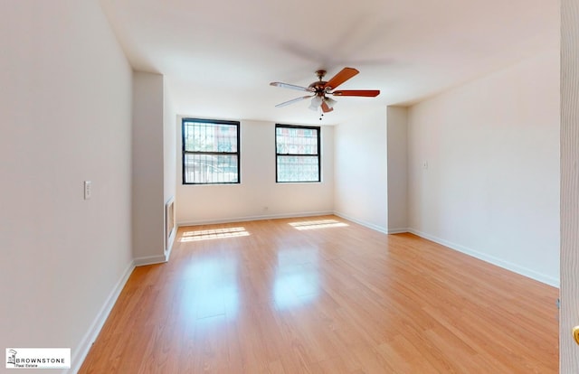 spare room featuring ceiling fan, baseboards, and light wood-style floors