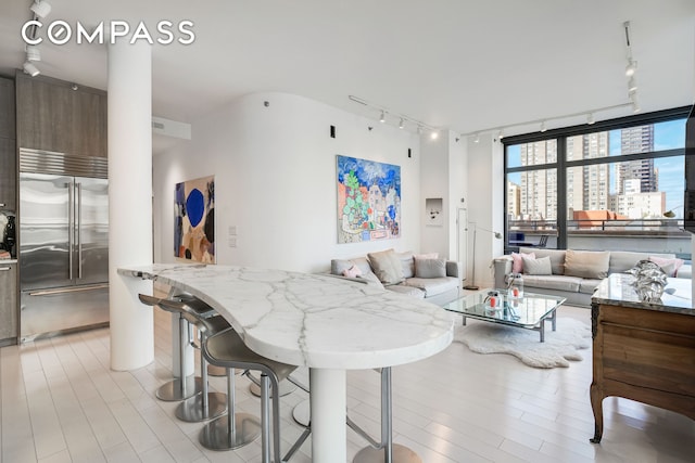 450 E 83rd St Unit 6B, New York City, NY 10028 - kitchen featuring stainless steel built in refrigerator, track lighting, open floor plan, light wood-style flooring, and a wall of windows