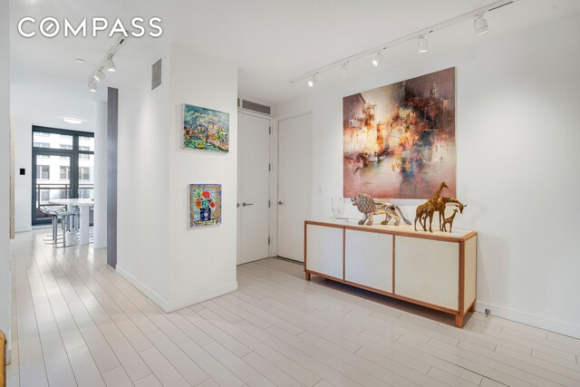 hall featuring track lighting and baseboards