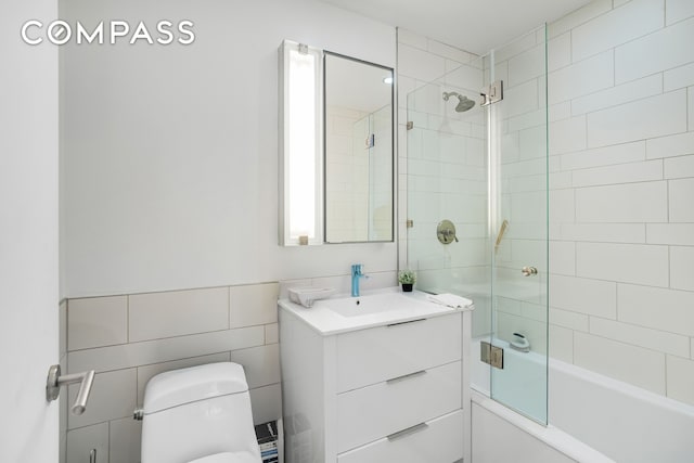 450 E 83rd St Unit 6B, New York City, NY 10028 - bathroom featuring vanity, toilet, bath / shower combo with glass door, and tile walls