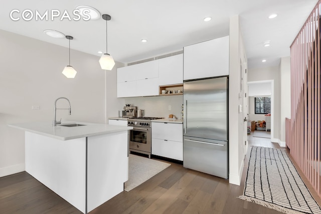kitchen featuring high quality appliances, a sink, white cabinets, dark wood-style flooring, and recessed lighting