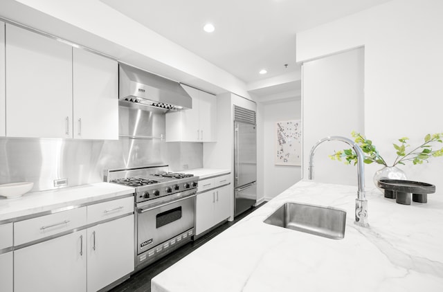 44 Laight St Unit 6C, New York City, NY 10013 - kitchen featuring wall chimney exhaust hood, high quality appliances, recessed lighting, white cabinetry, and light stone counters