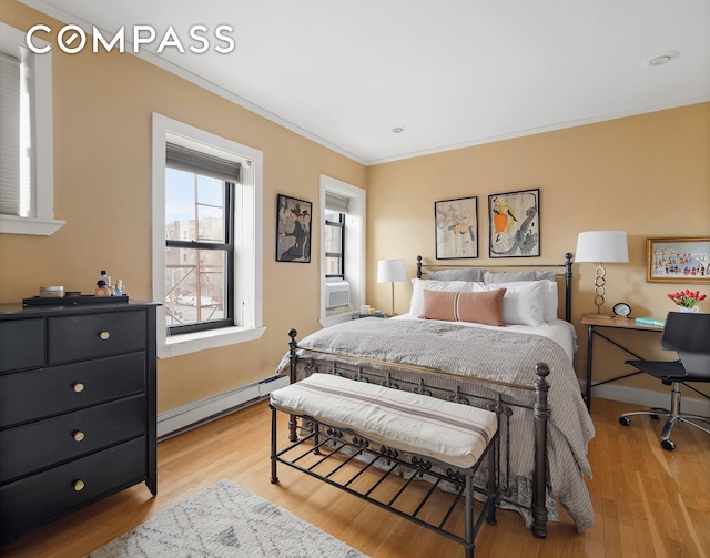 bedroom with crown molding, baseboard heating, baseboards, ensuite bath, and light wood-style flooring