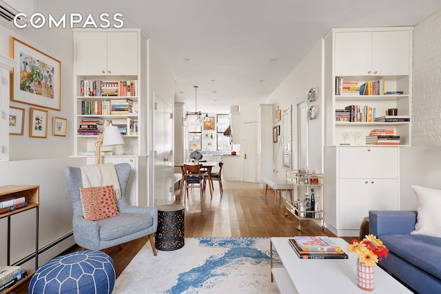 sitting room featuring a baseboard heating unit and wood finished floors