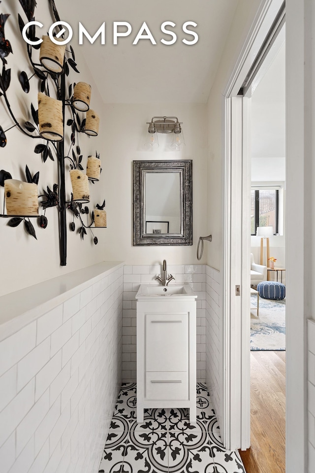 bathroom with vanity, tile patterned floors, tile walls, and a wainscoted wall