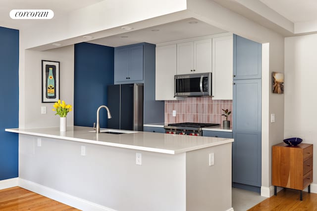416 E 11th St Unit 4A, New York City, NY 10009 - kitchen with stainless steel microwave, a sink, freestanding refrigerator, a peninsula, and backsplash