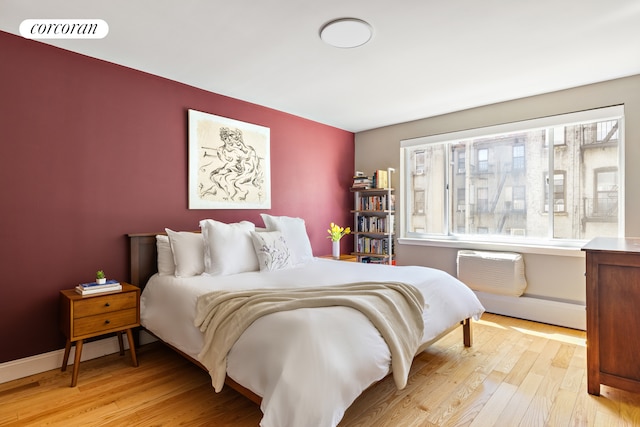 416 E 11th St Unit 4A, New York City, NY 10009 - bedroom featuring multiple windows, light wood finished floors, baseboard heating, and a wall mounted AC