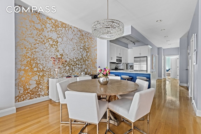 330 Bergen St Unit 3D, New York City, NY 11217 - dining room with wallpapered walls, a chandelier, light wood-type flooring, baseboards, and an accent wall