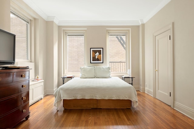 bedroom with baseboards, ornamental molding, and light wood finished floors