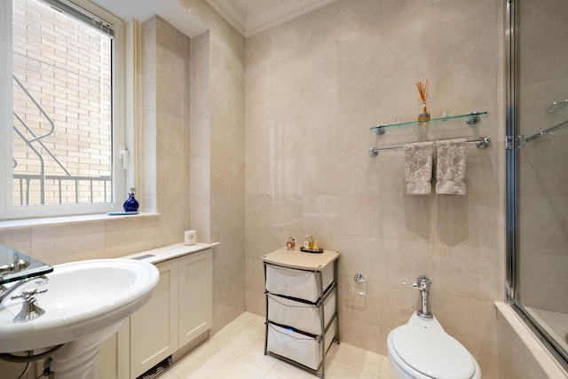 bathroom featuring a sink, toilet, tile patterned floors, tile walls, and ornamental molding