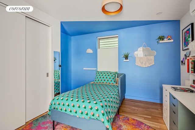 bedroom featuring wood finished floors and a wall mounted AC