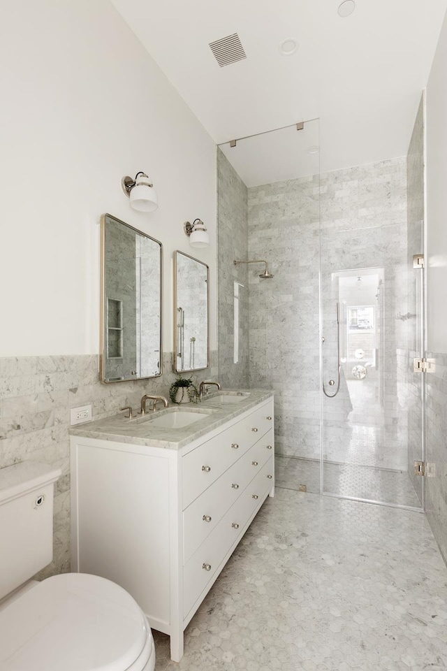 bathroom with toilet, visible vents, a shower stall, and a sink