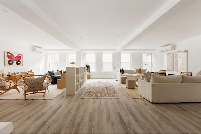 living area with beamed ceiling, an AC wall unit, and light wood-type flooring