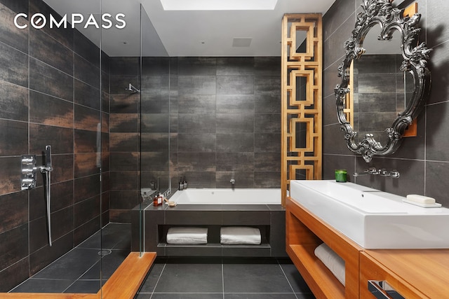 bathroom featuring tile patterned flooring, tiled shower, vanity, a tub to relax in, and tile walls