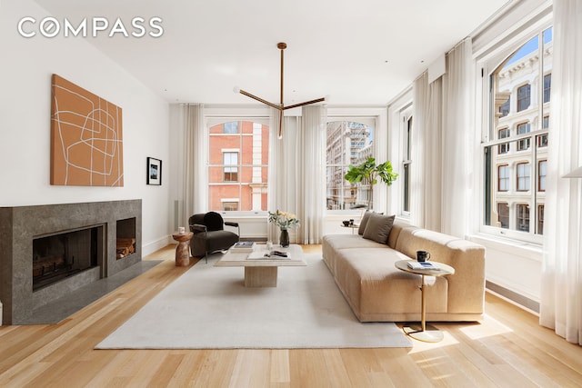 living area featuring wood finished floors, a fireplace with flush hearth, and baseboards
