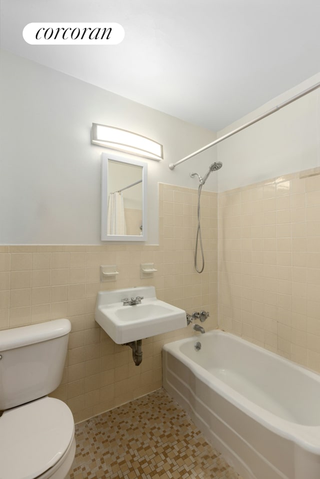 2915 W 5th St Unit 22C, New York City, NY 11224 - bathroom featuring tile walls, a sink, toilet, bathtub / shower combination, and wainscoting