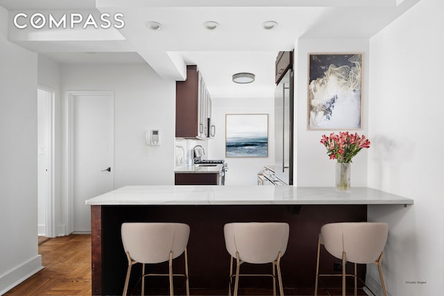 54 W 16th St Unit 6F, New York City, NY 10011 - kitchen featuring a breakfast bar area, a peninsula, recessed lighting, and light stone counters