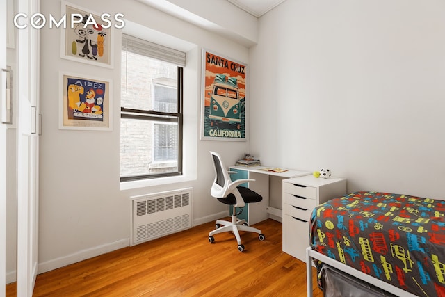 bedroom featuring radiator, light wood-type flooring, and baseboards
