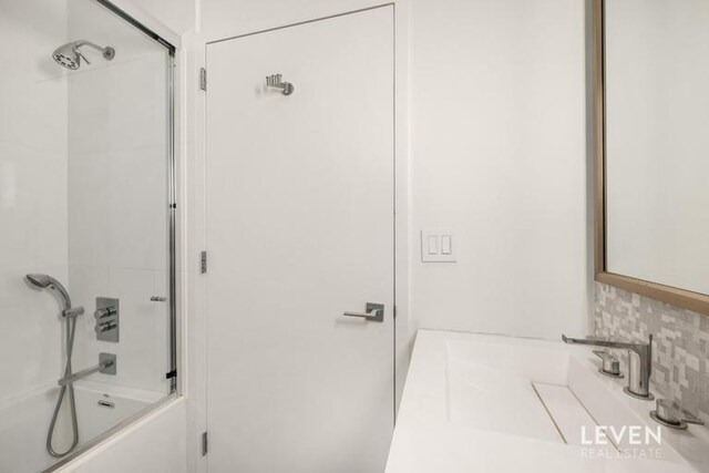 235 E 55th St Phb, Phb, New York City, NY 10022 - bathroom with backsplash, shower / bath combination with glass door, and vanity