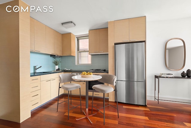206 E 95th St Unit 10B, New York City, NY 10128 - kitchen featuring freestanding refrigerator, dark wood finished floors, a sink, tasteful backsplash, and dark countertops