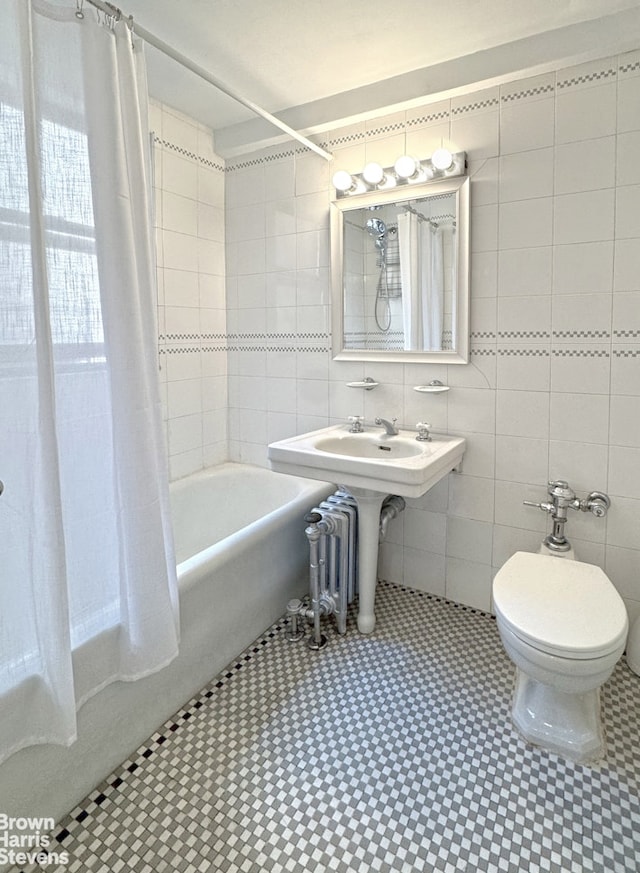 bathroom with tile walls, shower / bathtub combination with curtain, toilet, and tile patterned floors
