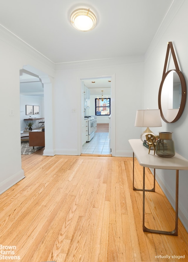 hall featuring baseboards, arched walkways, and wood finished floors