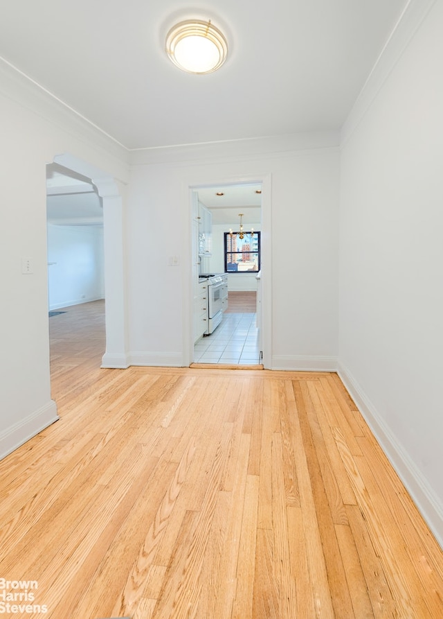 spare room with baseboards, arched walkways, and wood finished floors