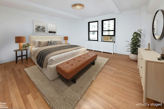 bedroom featuring light wood-style floors, radiator, and beamed ceiling