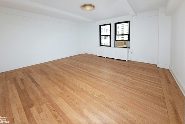 unfurnished room with light wood-style flooring and beamed ceiling